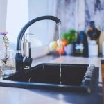 A kitchen sink with a faucet running water