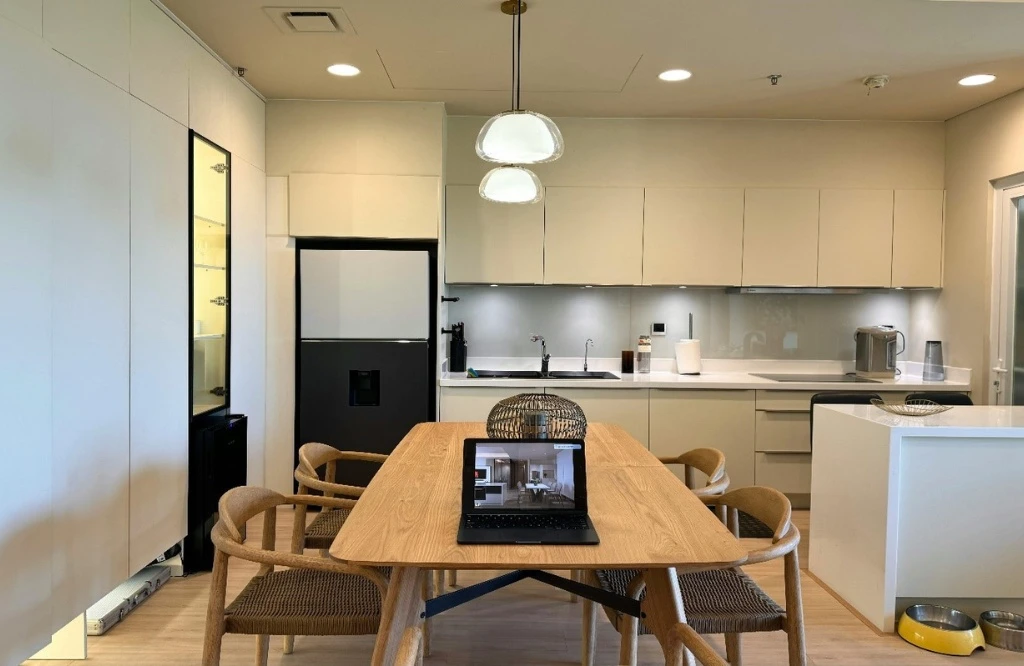 Modern kitchen and dining area with laptop on table.