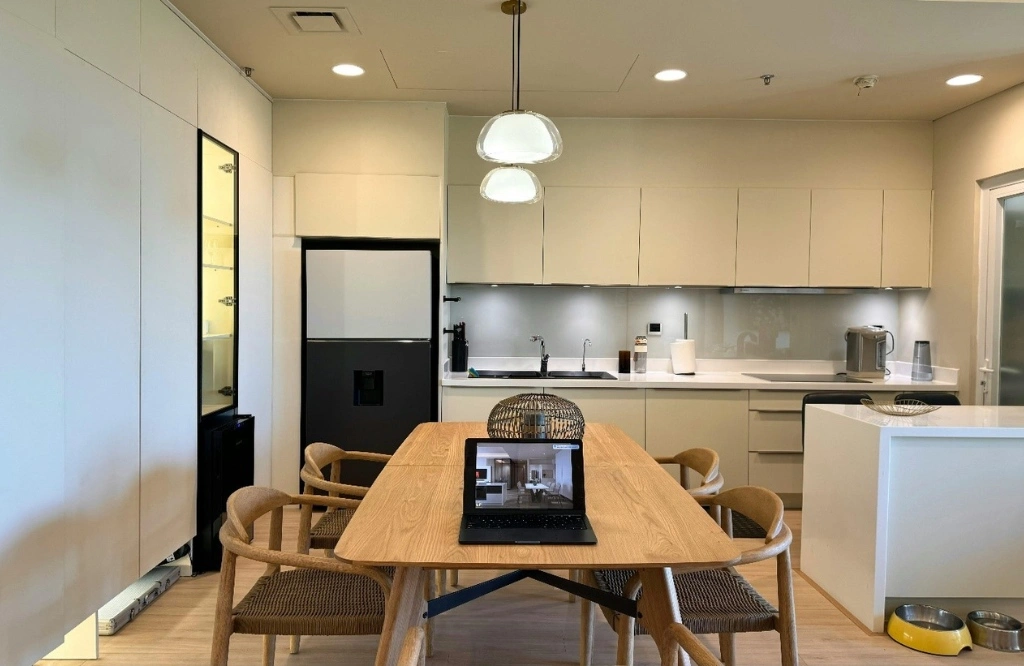 A well-designed kitchen and dining area with a laptop on the table, highlighting a practical and efficient layout.