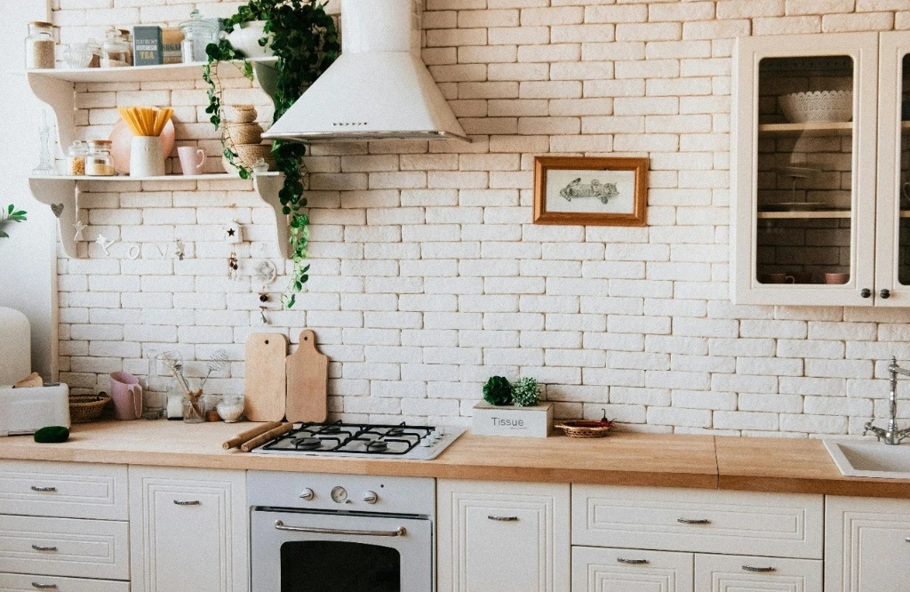 Stylish kitchen featuring white brick walls and wooden cabinets, blending rustic and contemporary elements.
