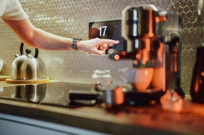 A person operating an electronic timer on a kitchen counter with integrated touchscreens.