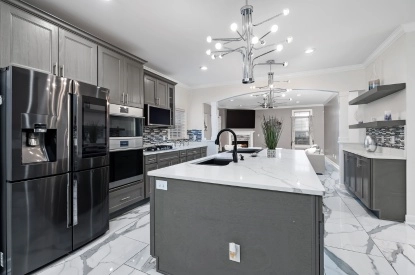 A kitchen with gray cabinets and marble counter tops, featuring a smart refrigerator for Advanced Connectivity.