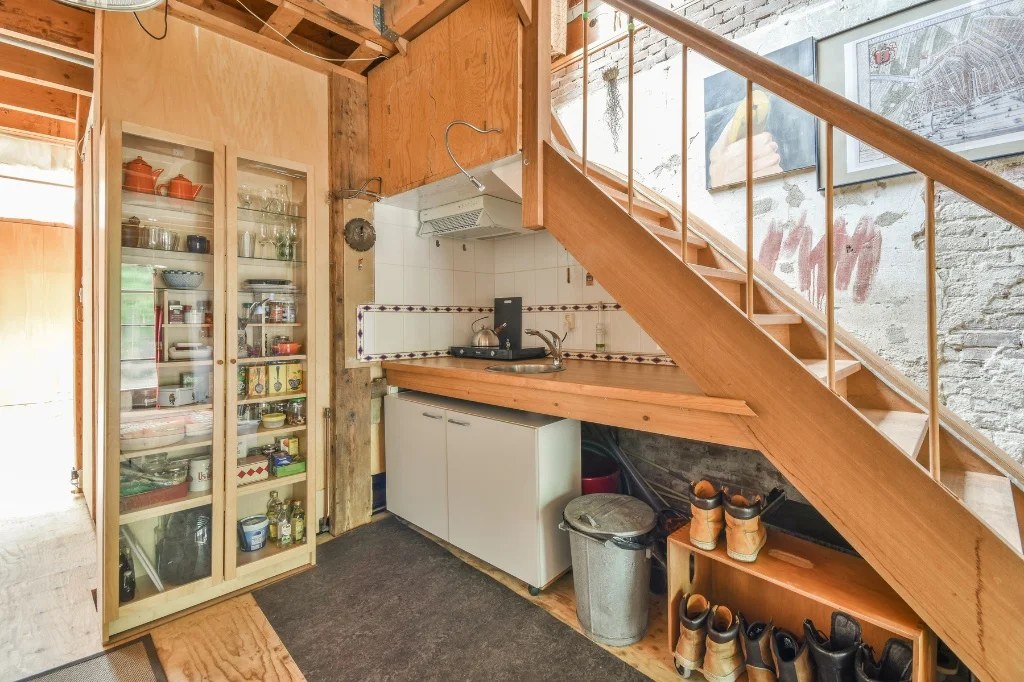 Use Space Under the Stairs in the Kitchen featuring wooden stairs and a fridge.