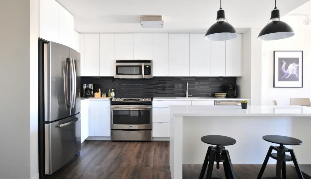 A modern kitchen with white cabinets and black counter tops.