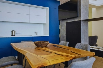 A modern kitchen featuring bold navy blue cabinets and a wooden table, complemented by blue walls for a stylish ambiance.