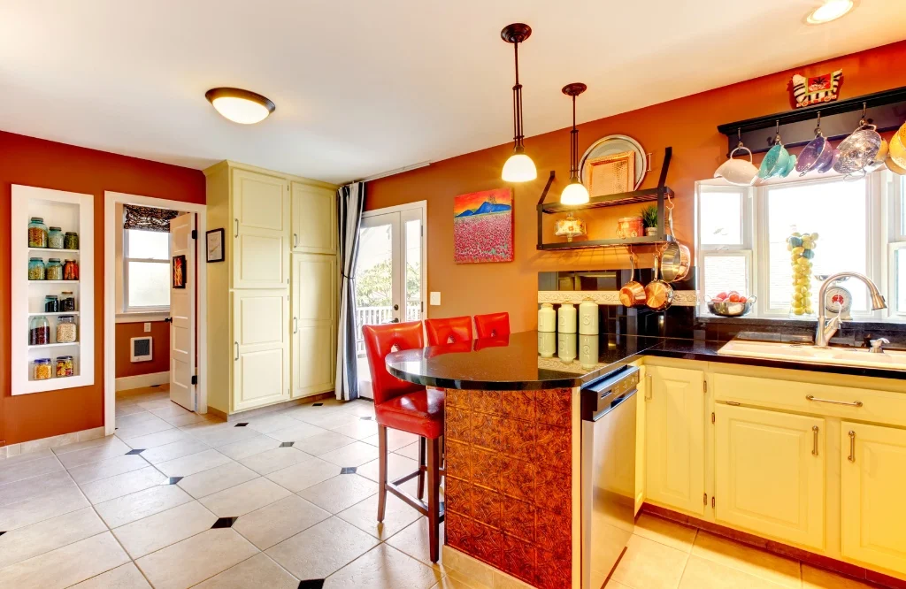 Kitchen featuring warm color scheme, with orange walls and black counter top.