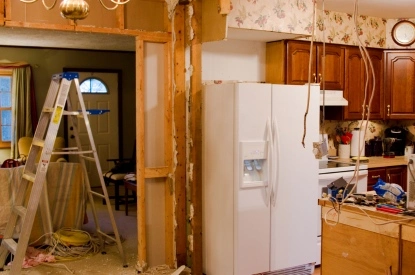 A kitchen undergoing renovation, showcasing cabinets and appliances being removed during the demolition process.