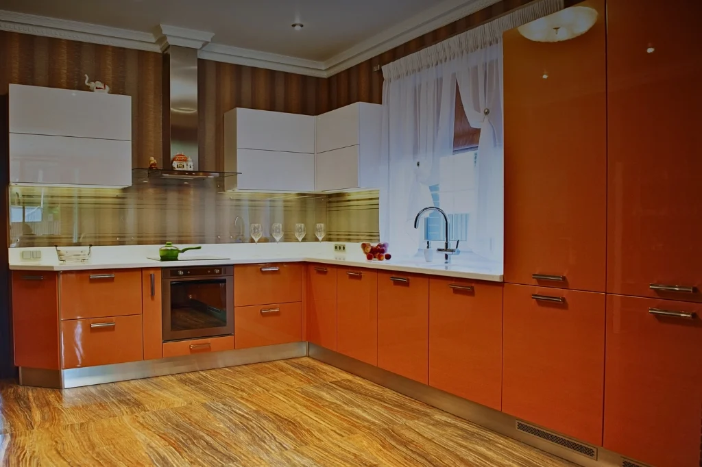 A contemporary kitchen adorned with bright orange cabinets and elegant wood flooring, perfect for a cheerful cooking space.