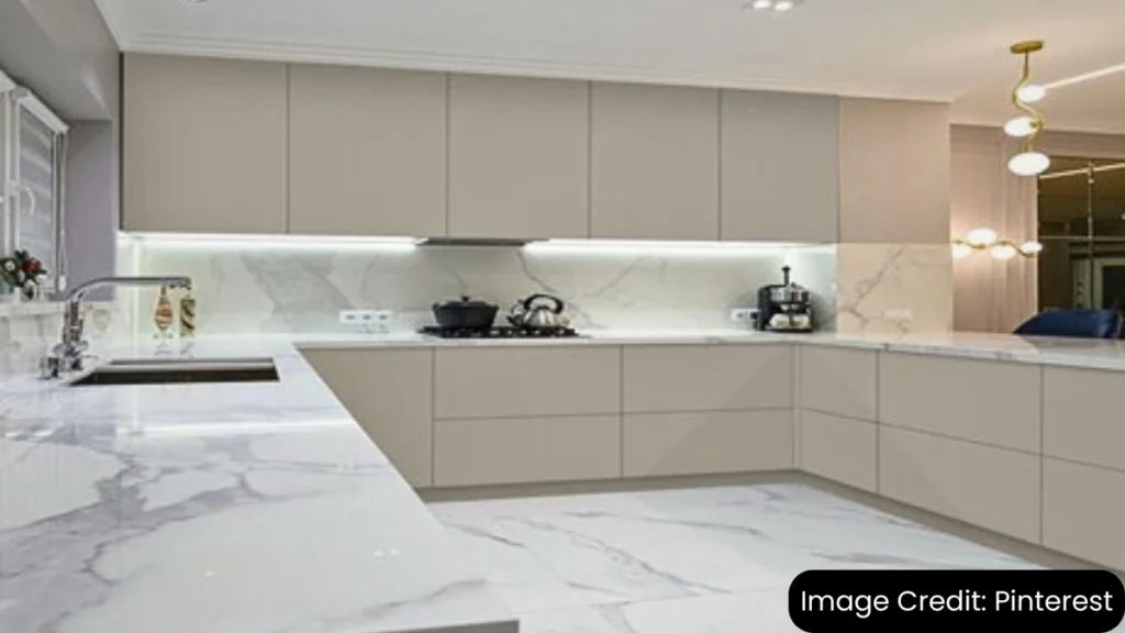 Modern kitchen with sleek flat-panel cabinets, white marble countertops, and under-cabinet lighting.