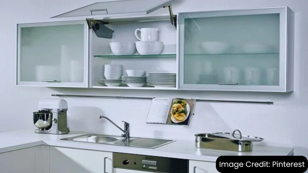 Modern glass-front kitchen cabinets with organized dishware in a sleek white kitchen design.