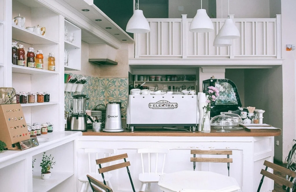 A stylish coffee shop showcasing white walls and shelves, perfect for guiding your kitchen renovation plans.