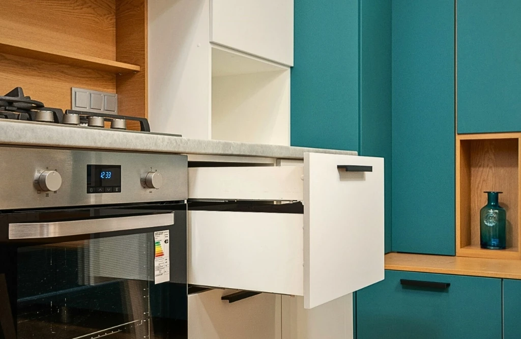 A kitchen featuring a stove and sink, illustrating the process of replacing cabinets with open shelves for better organization.