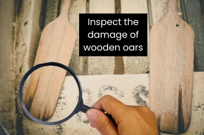 Someone uses a magnifying glass to inspect a wooden oar, focusing on the condition of the wooden oars.