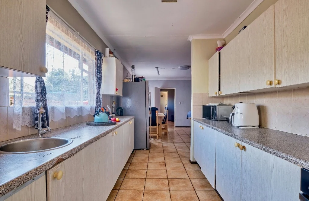 A narrow kitchen featuring a sink, microwave, and refrigerator showcasing features of new installations during kitchen renovation.