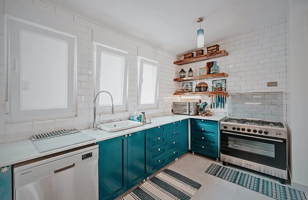 A well-designed kitchen with blue cabinets, white tiled walls, and open shelving, offering a fresh and airy feel.