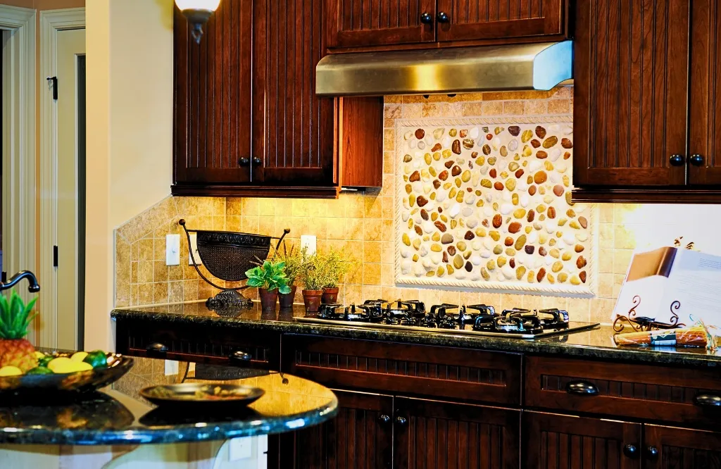 A contemporary kitchen with a stove and sink, complemented by decorative backsplashes and wall art for aesthetic enhancement.