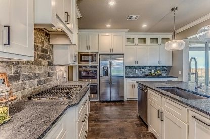 A stylish kitchen showcasing granite countertops and sleek stainless steel appliances, perfect for larger home kitchen concepts.