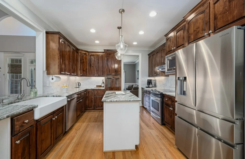 A wide kitchen showcasing stainless steel appliances and wood cabinets, optimized for maximum storage capacity.