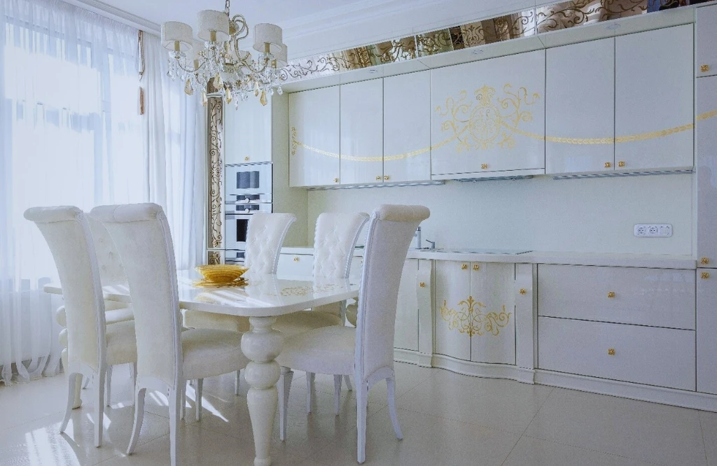 Perfect kitchen cabinet size according to your kitchen: A white kitchen featuring gold accents and a stylish dining table.