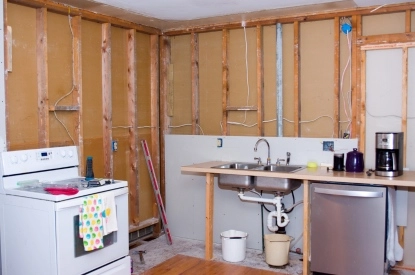 A well-equipped kitchen with a stove, sink, and refrigerator illustrates the plumbing and electrical aspects of the renovation.