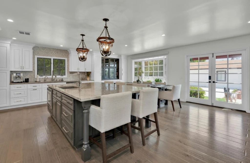 A spacious kitchen featuring white cabinets and hardwood floors, showcasing a modern remodeling design.