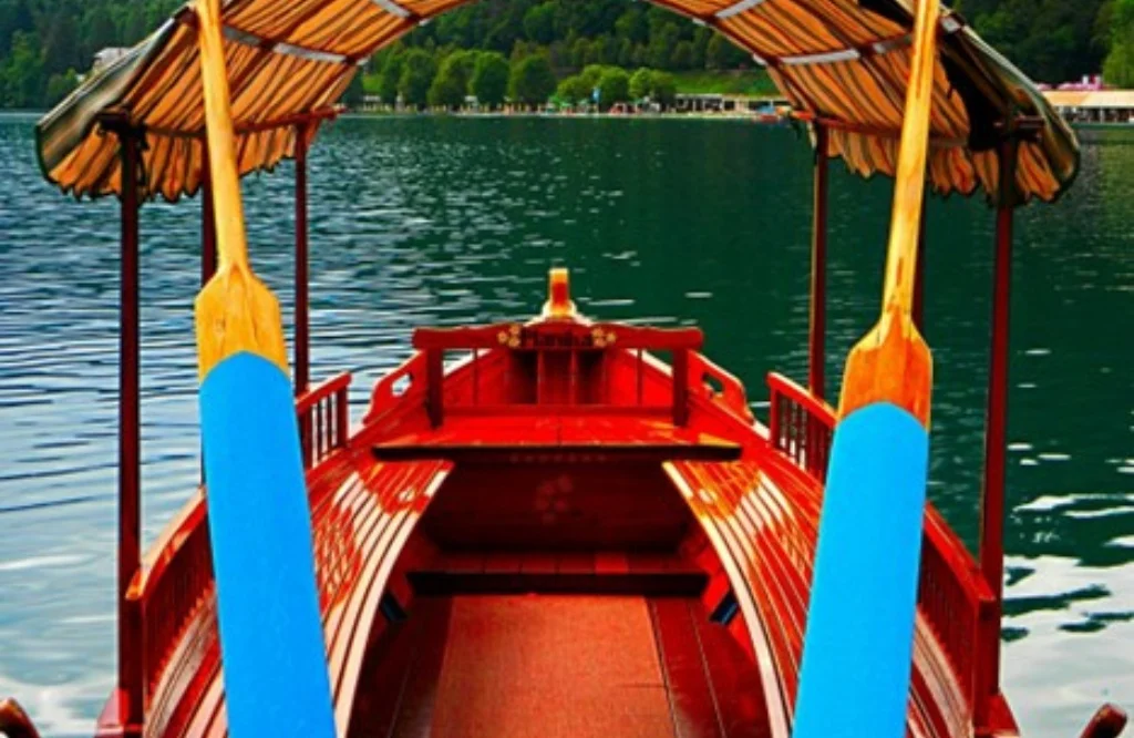 A boat equipped with two old wooden oars, recently restored, is peacefully situated on the water, surrounded by nature.