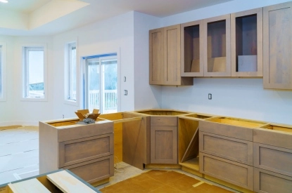 A kitchen undergoing renovation, featuring unfinished cabinets and countertops, highlighting structural changes in the design.