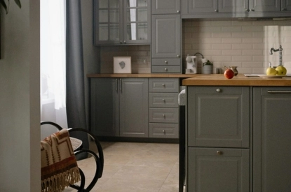 A modern kitchen featuring warm grey cabinets and a rustic wooden table, creating a cozy and inviting atmosphere.