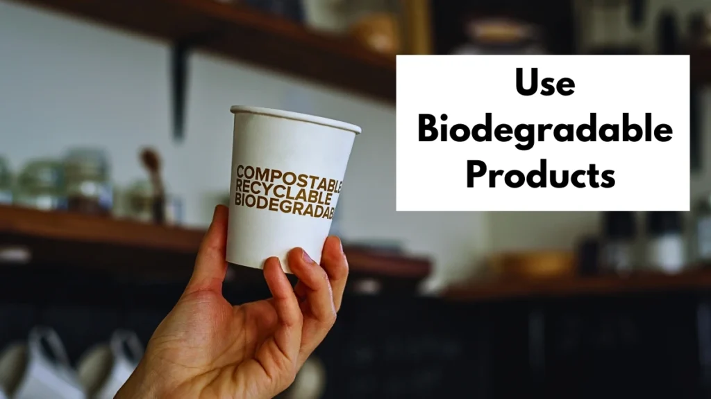 A hand is holding a biodegradable cup promoting eco-friendly product use for camping kitchen.