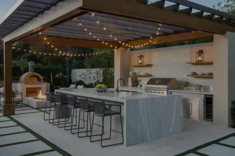 An elegant, modern outdoor kitchen layout ideas under a wooden pergola, featuring a large central island with built-in stainless steel appliances, a marble countertop, and stylish bar stools.