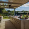 Modern open outdoor kitchen with cooling features, including a fan and shaded seating area.