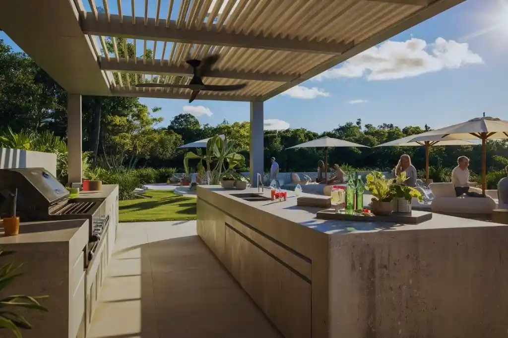 Modern open outdoor kitchen with cooling features, including a fan and shaded seating area.