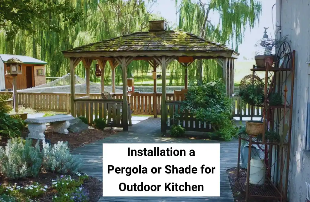 A wooden pergola providing shade in an outdoor kitchen area surrounded by greenery.