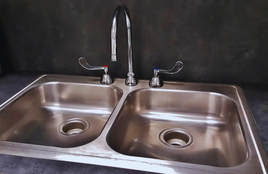 Stainless steel double sink with chrome faucet, ideal for heat resistance and durability.