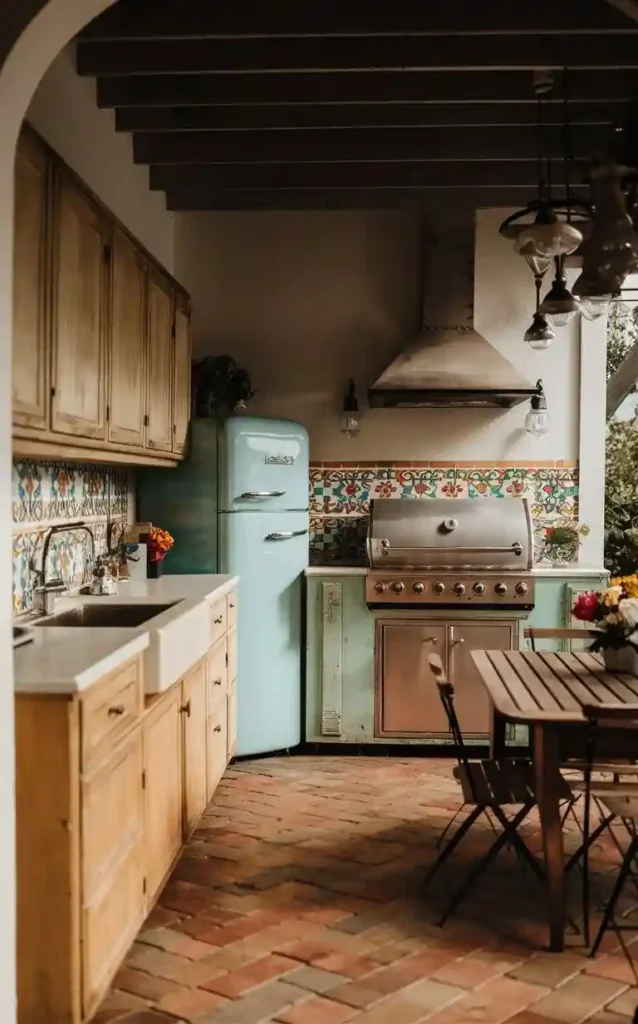 A vintage-inspired outdoor kitchen featuring a retro refrigerator, colorful tiles, and modern grill.